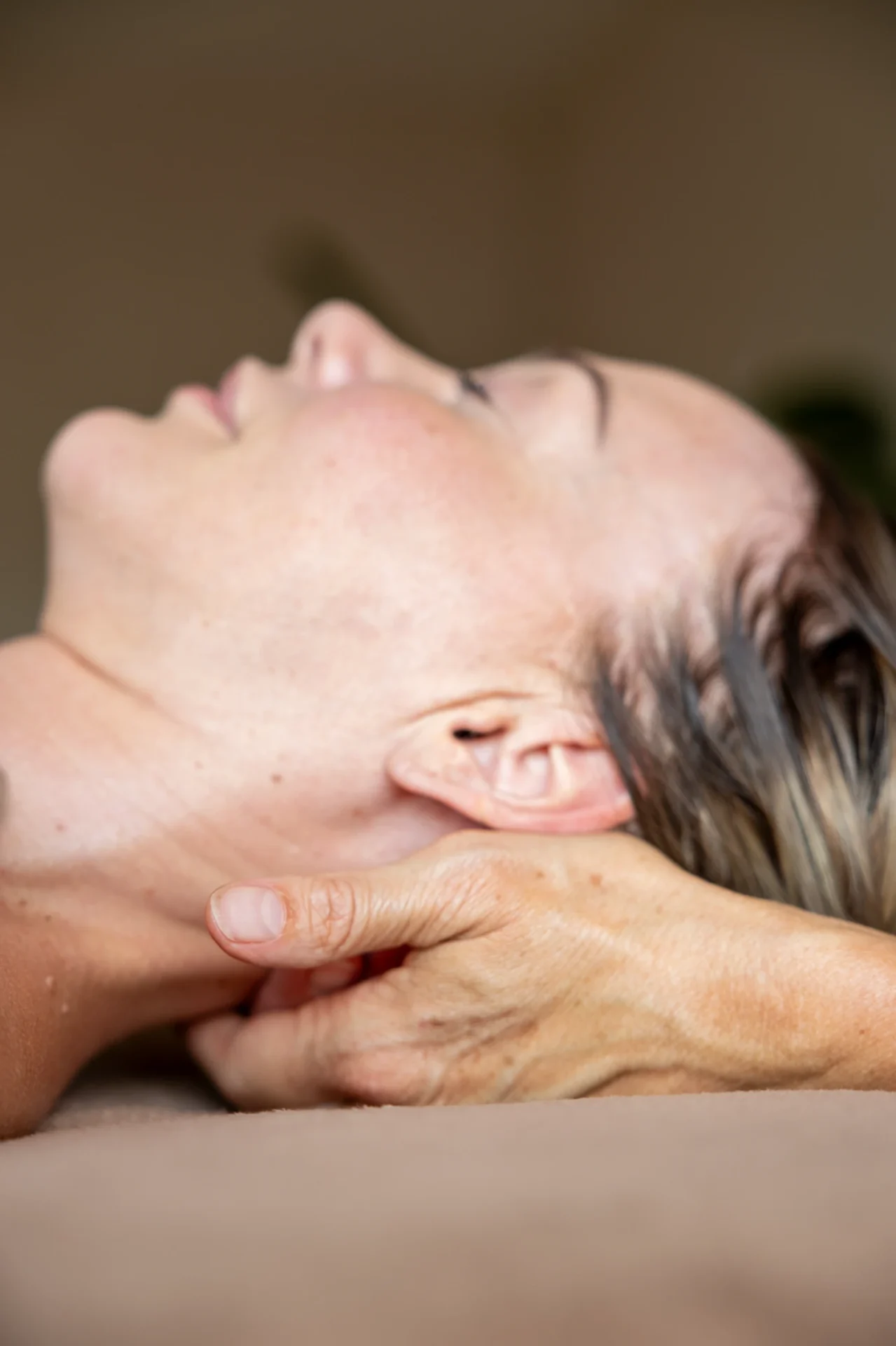 Handen ondersteunen nek en hoofd bij een craniosacrale behandeling